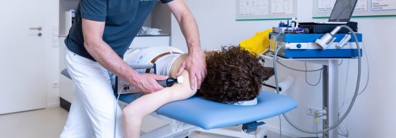 Dr. Eckard Hasch während der Matrix-Rythums-Therapie an einer Patientin, die auf dem Bauch liegt.