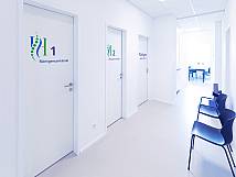Weißer Gang mit Wartebereichen und Türen zu den einzelnen Behandlungszimmern