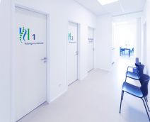 Weißer Gang mit Wartebereichen und Türen zu den einzelnen Behandlungszimmern